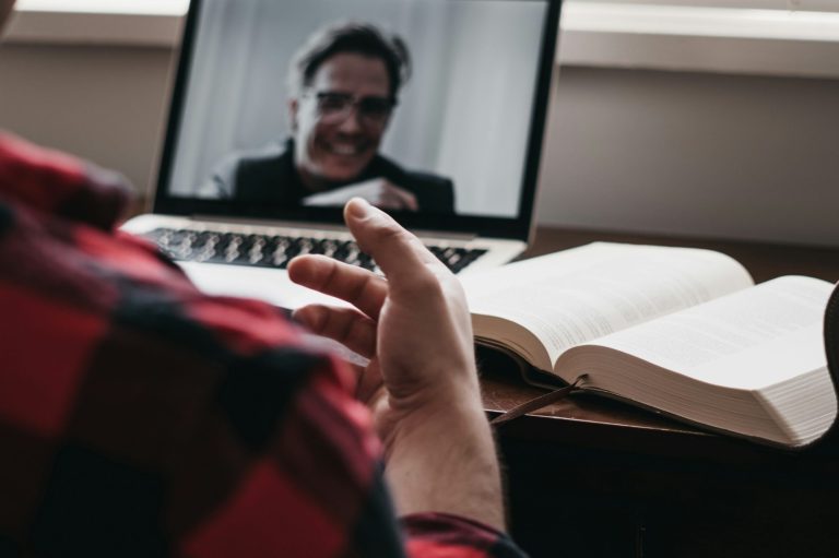 Looking over the shoulder of a laptop screen with another person on a video call.